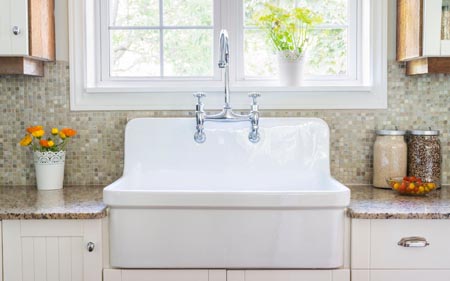 A white porcelain farmhouse sink with a double-handle faucet.