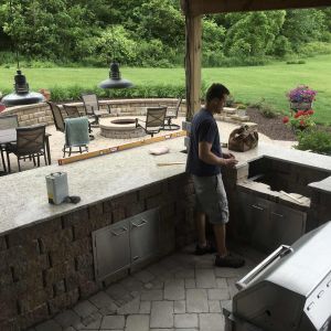 Expansive outdoor kitchen with dark gray granite countertops, built-in stainless steel grill, and appliances